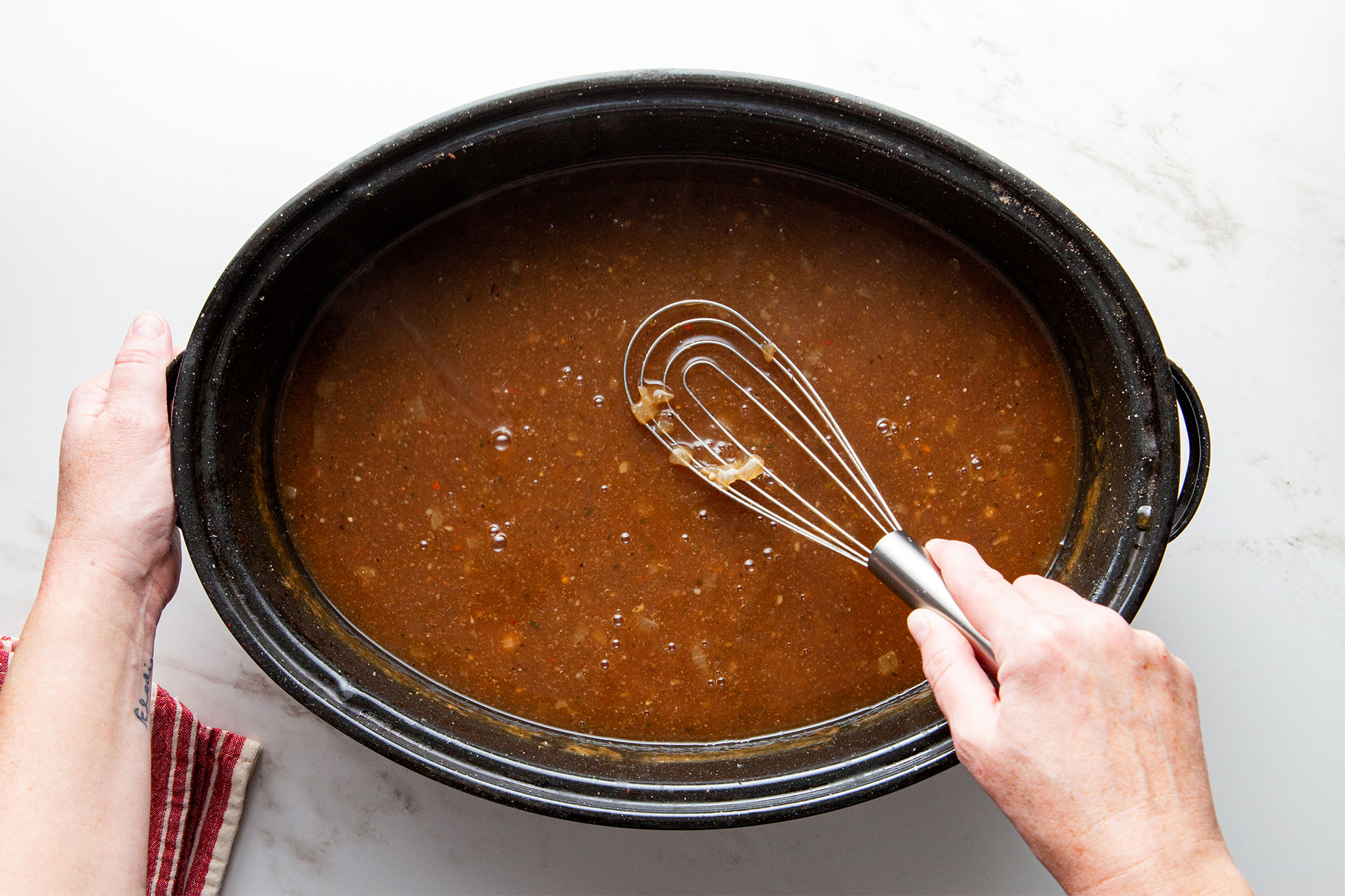 Using a whisk to stir the gravy.
