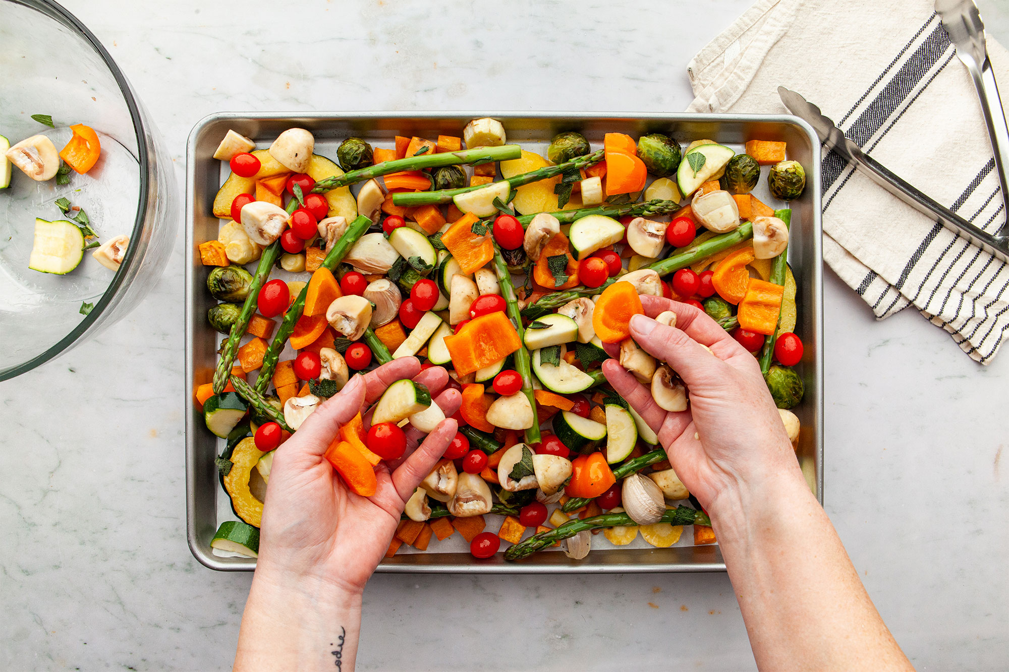 Adding the vegetables to the sheet pan for roasting.