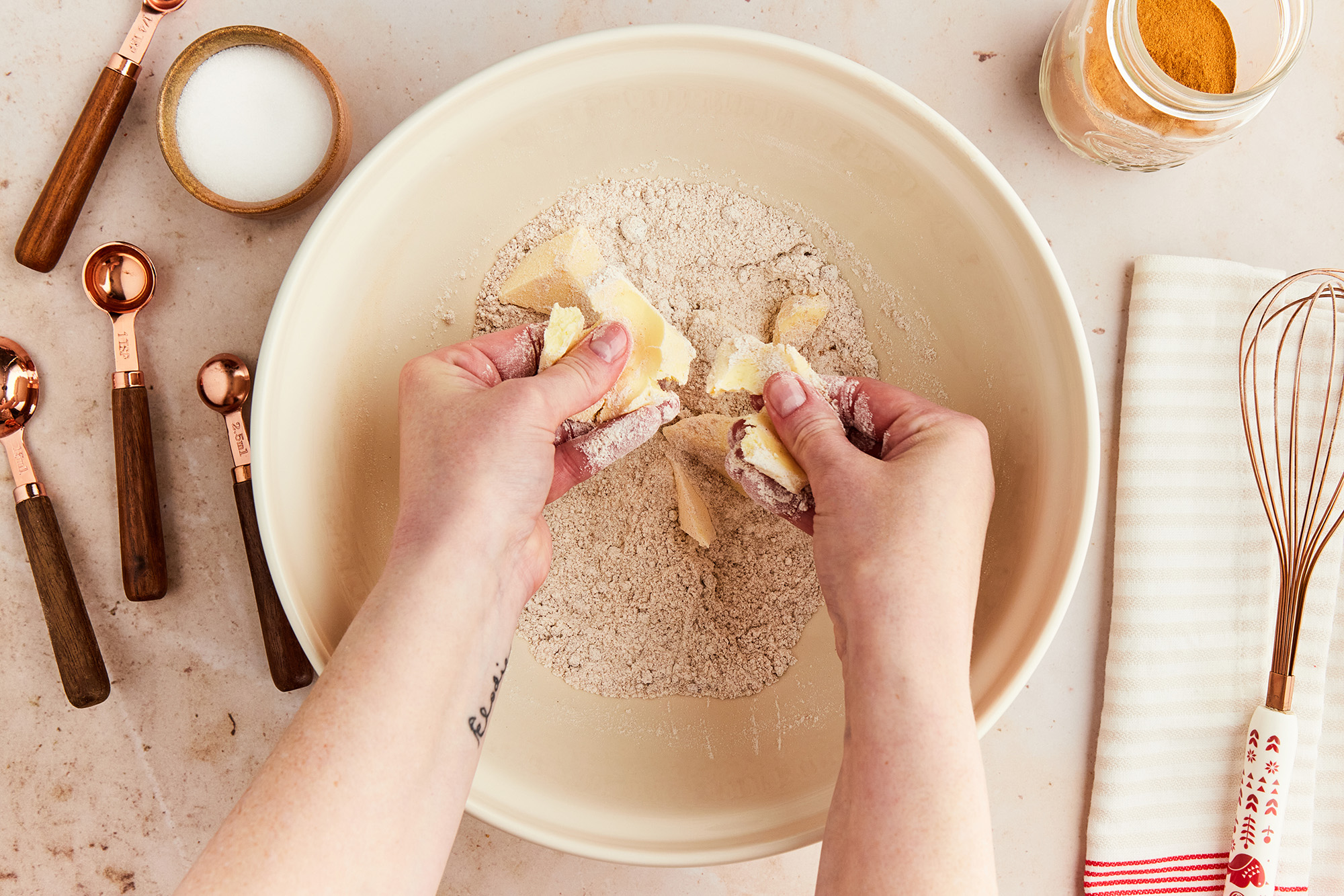 Using hands to break apart ingredients into a bowl.