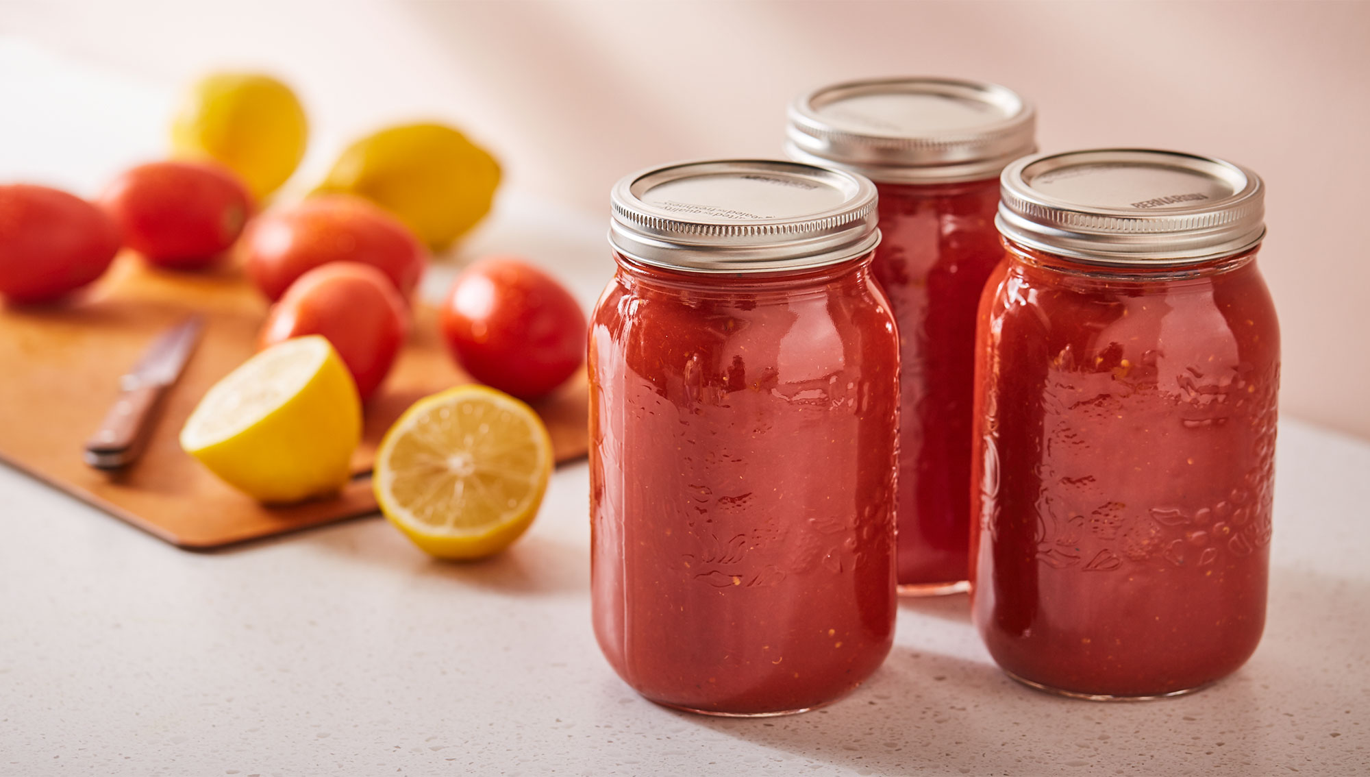 Jars of tomato preserves with whole tomatoes and lemons.
