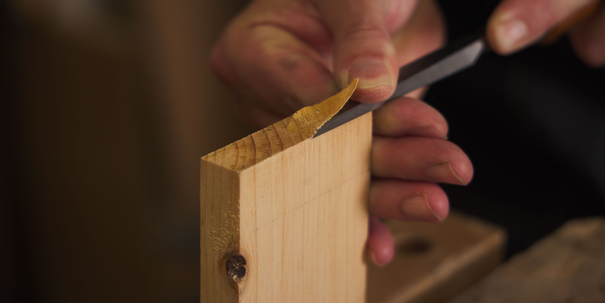 Testing the sharpness of a chisel by slicing a shaving off the end grain of a board