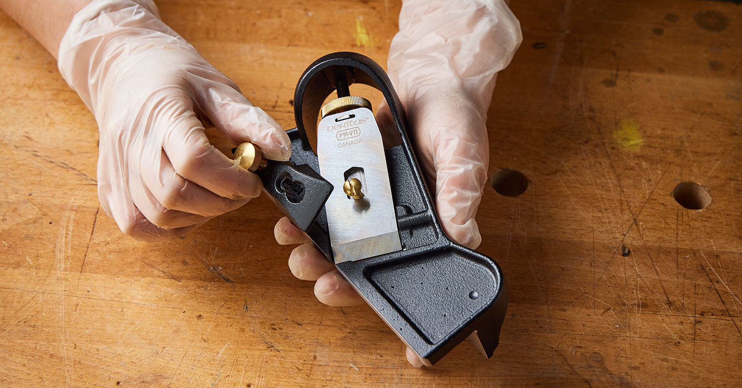 A user begins disassembling a  Veritas iron edge-trimming plane by removing the lever cap.