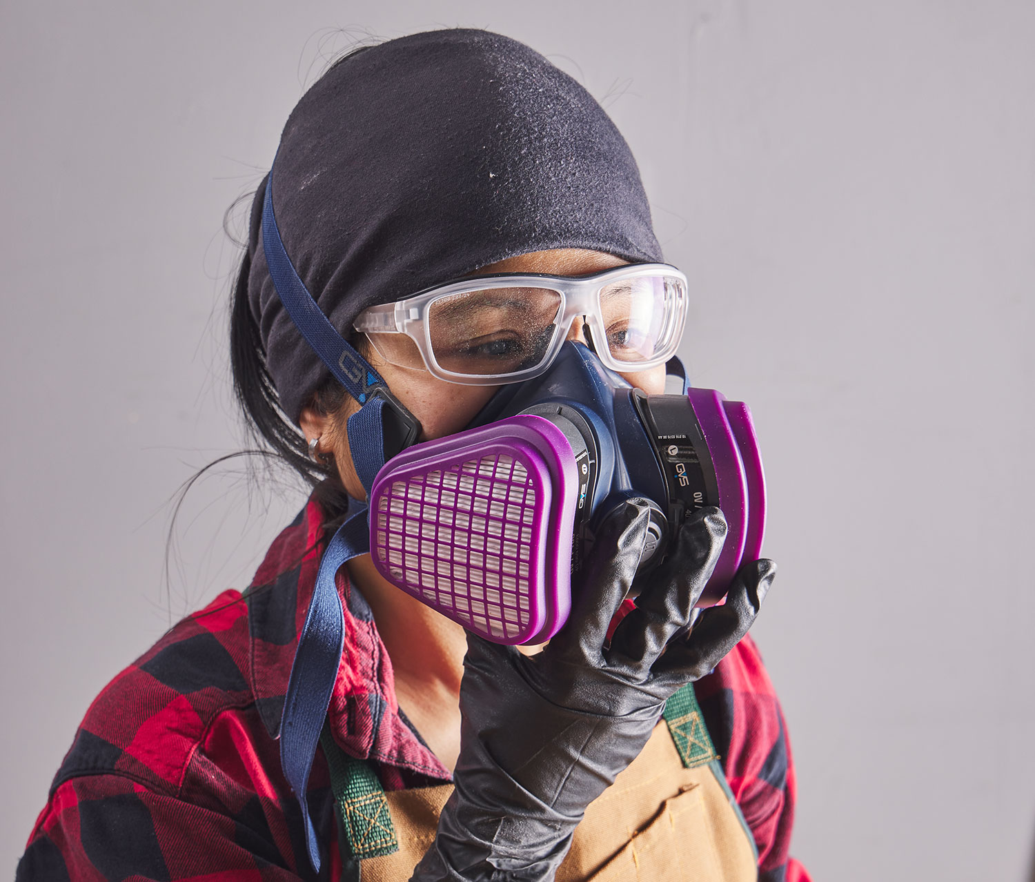 Woman wearing gloves, a respirator, and safety glasses.