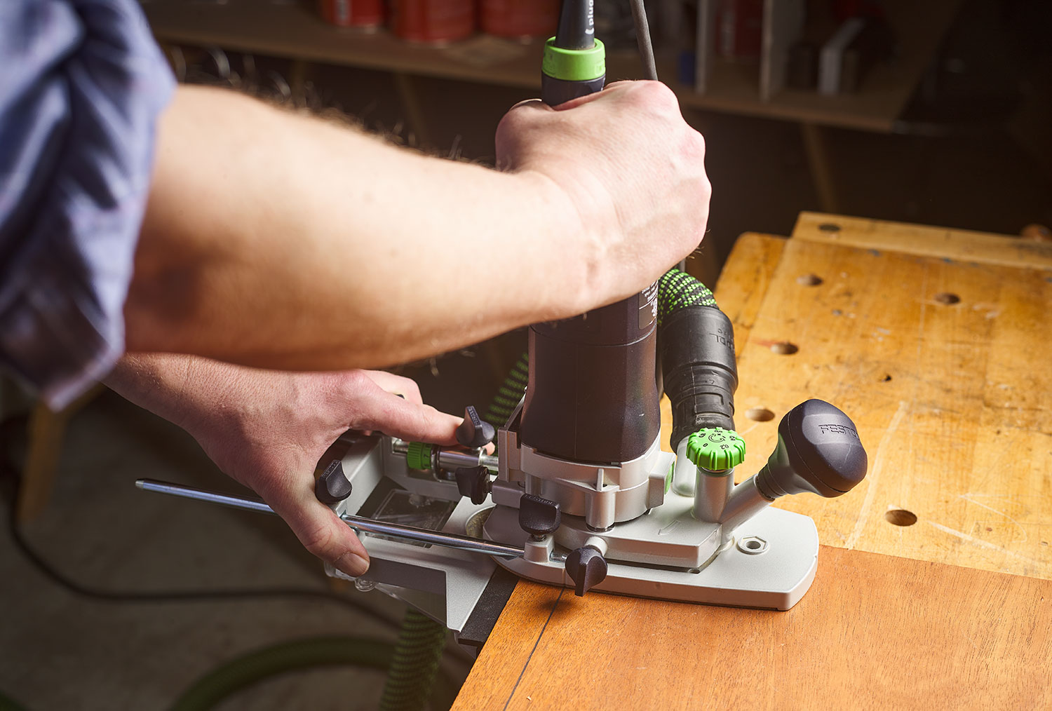 A woodworker using the router to mill a groove in a piece of plywood