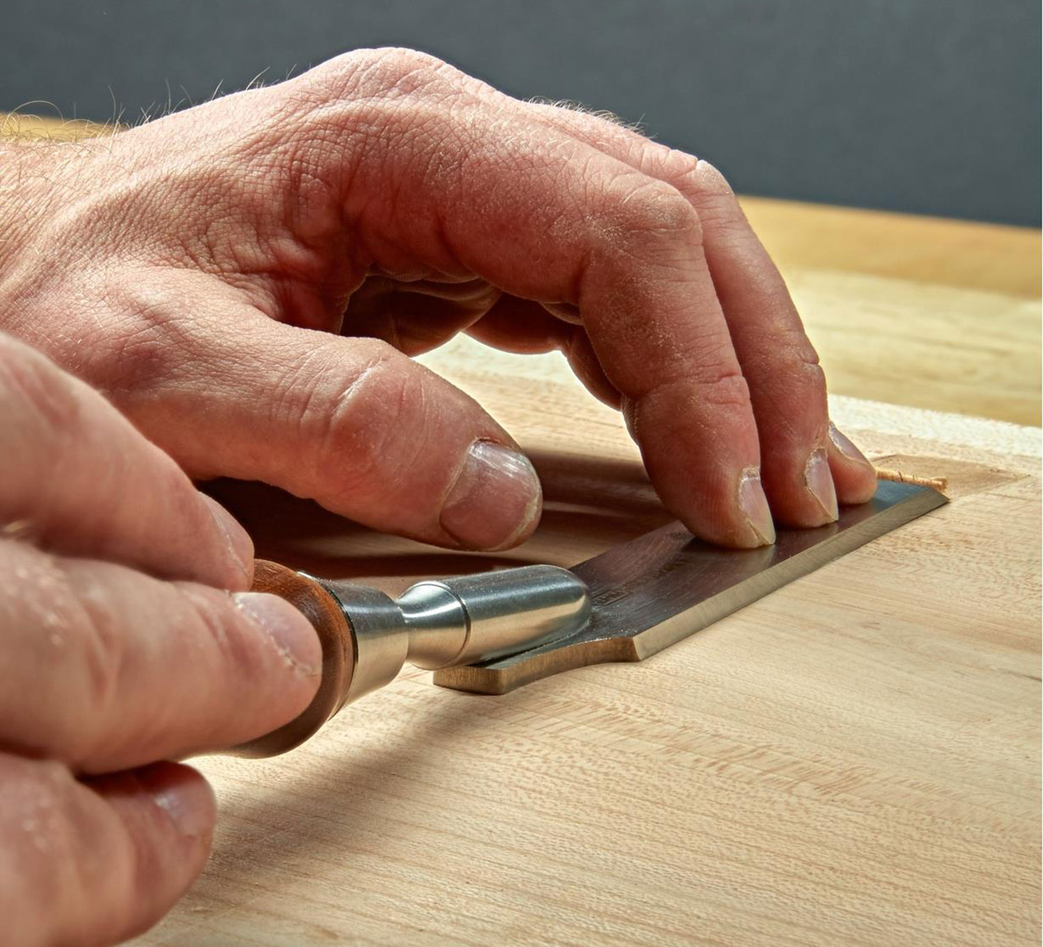 Correct grip for a flushing chisel- pushing the handle with the dominant hand, and keeping the blade against the work with the non-dominant hand.