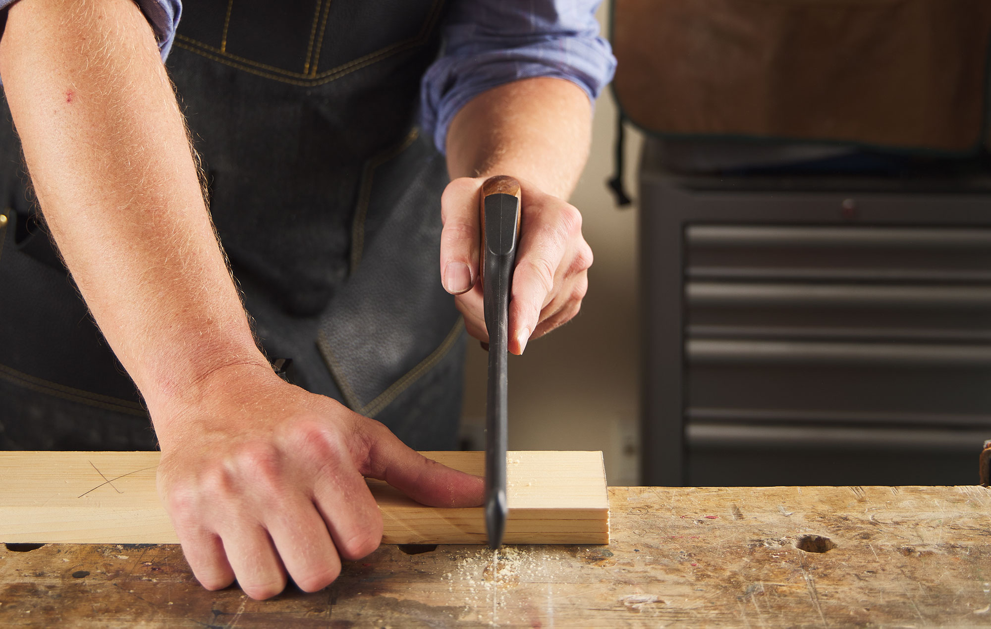 A man with his arm aligned with the saw making a cut