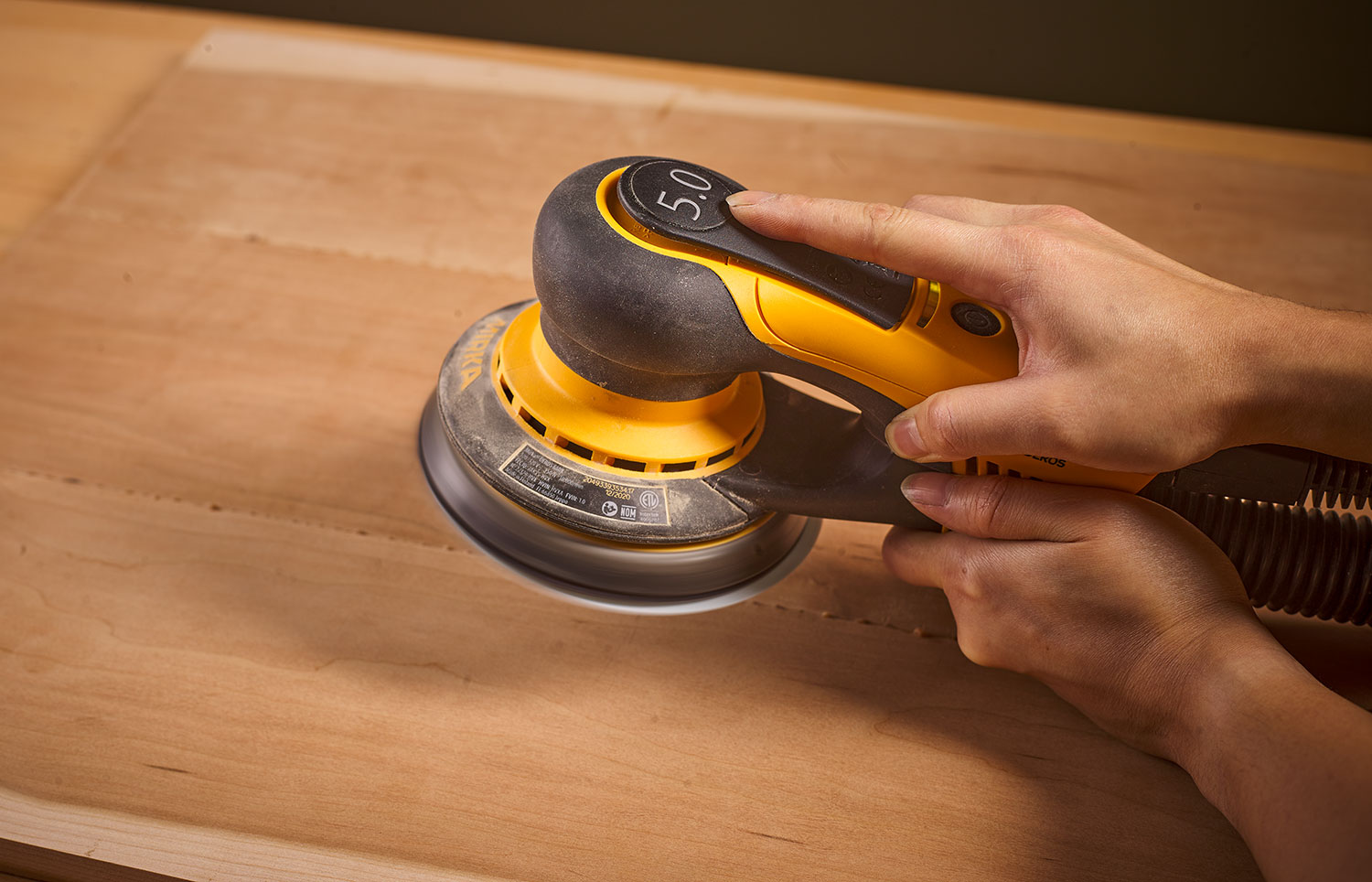The upper control paddle on a Mirka DEROS sander being partially pressed down.