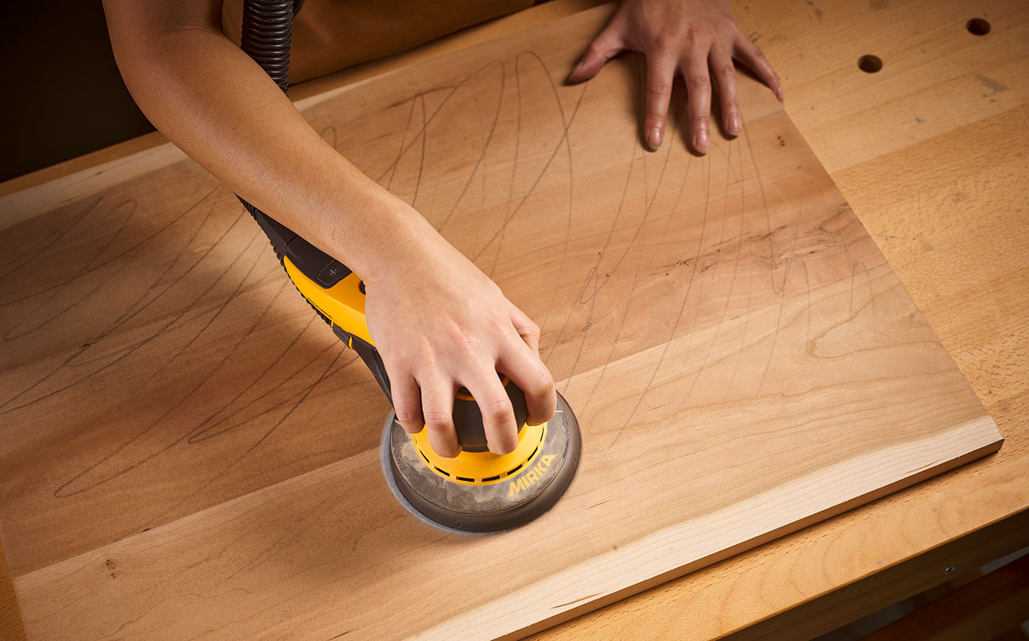 A board being sanded using a Mirka DEROS sander