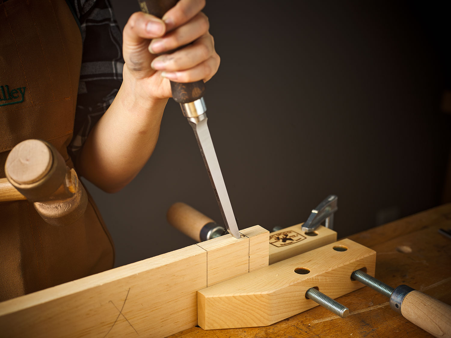 A mortise is being cut into a board using a Narex mortise chisel and a mallet.