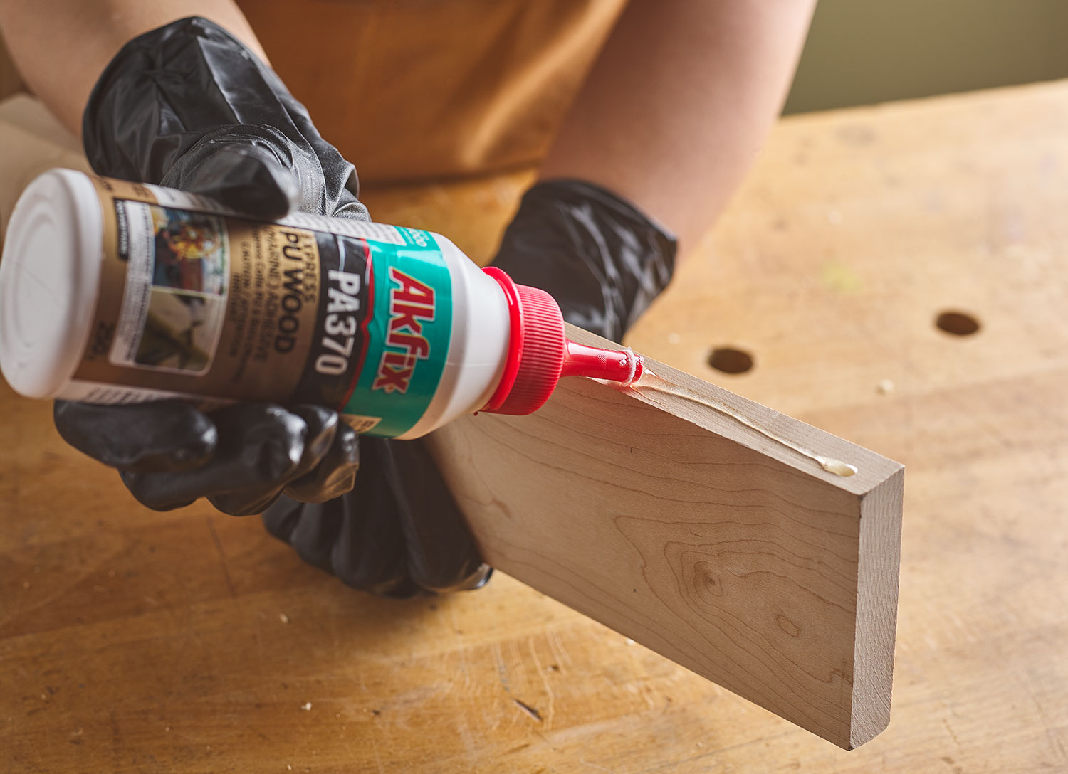 Polyurethane adhesive being applied to the edge of a wooden board.