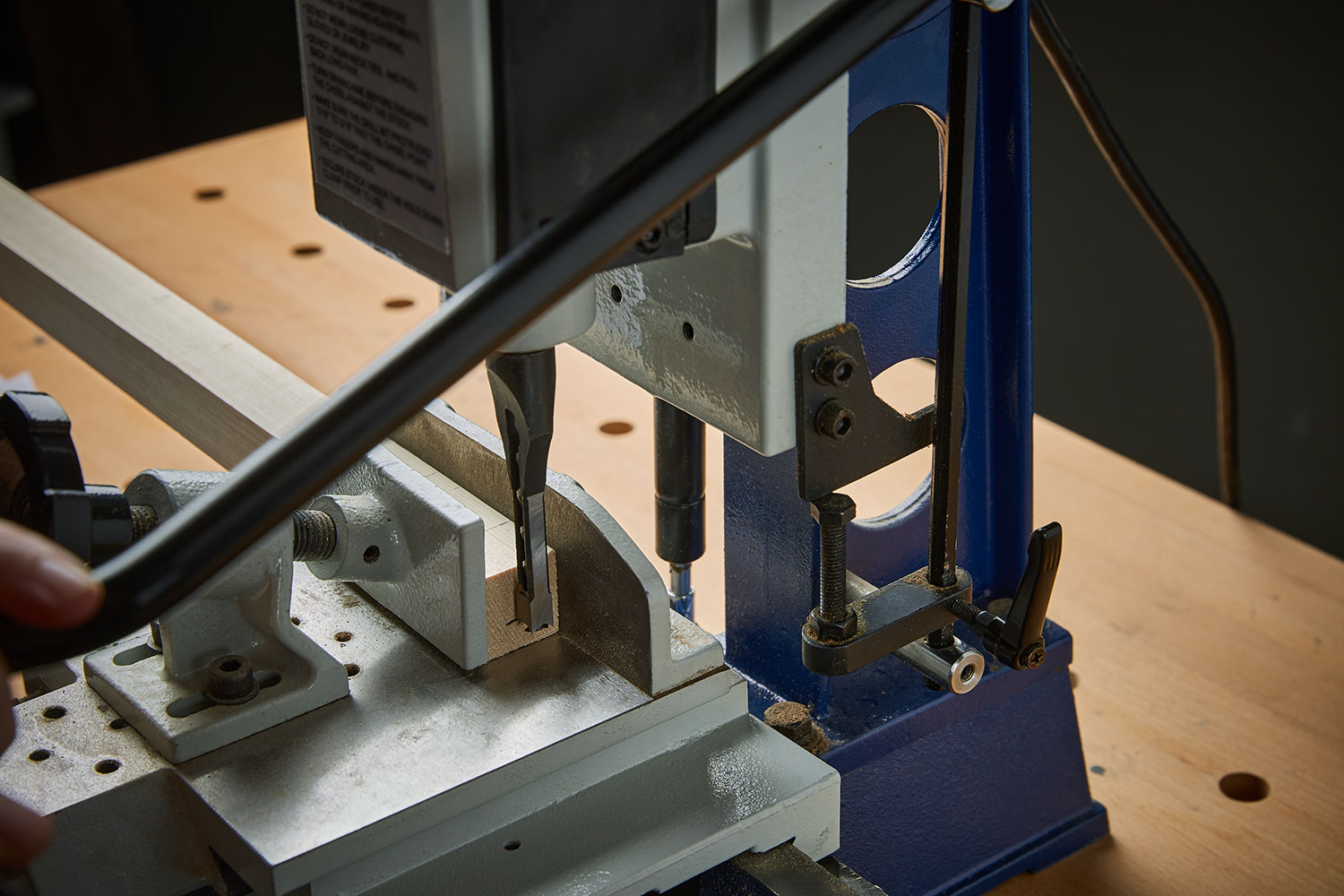 A board being used to set the depth stop on a mortise.