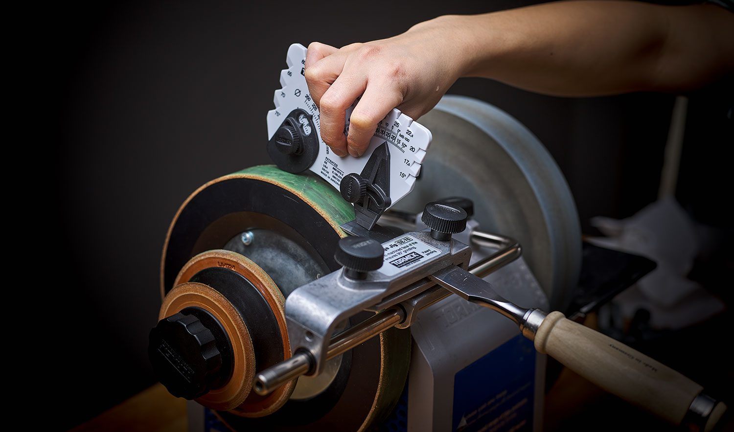 Using the angle-setter gauge to grind a chisel to a precise bevel angle on a T-8 sharpening machine.
