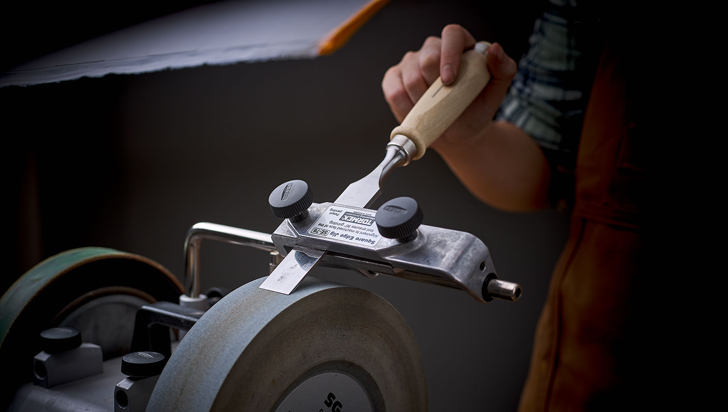 Sharpening a chisel on a T-8, showing the clearance between the grindstone and the square-end jig .