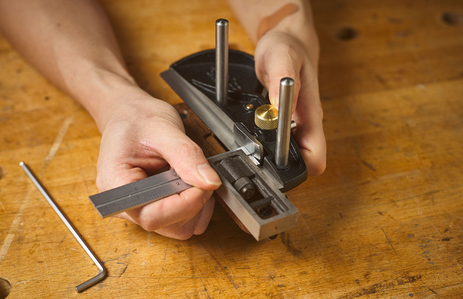 Registering a combination square against the skate of a box-maker’s plow plane to set the depth stop.