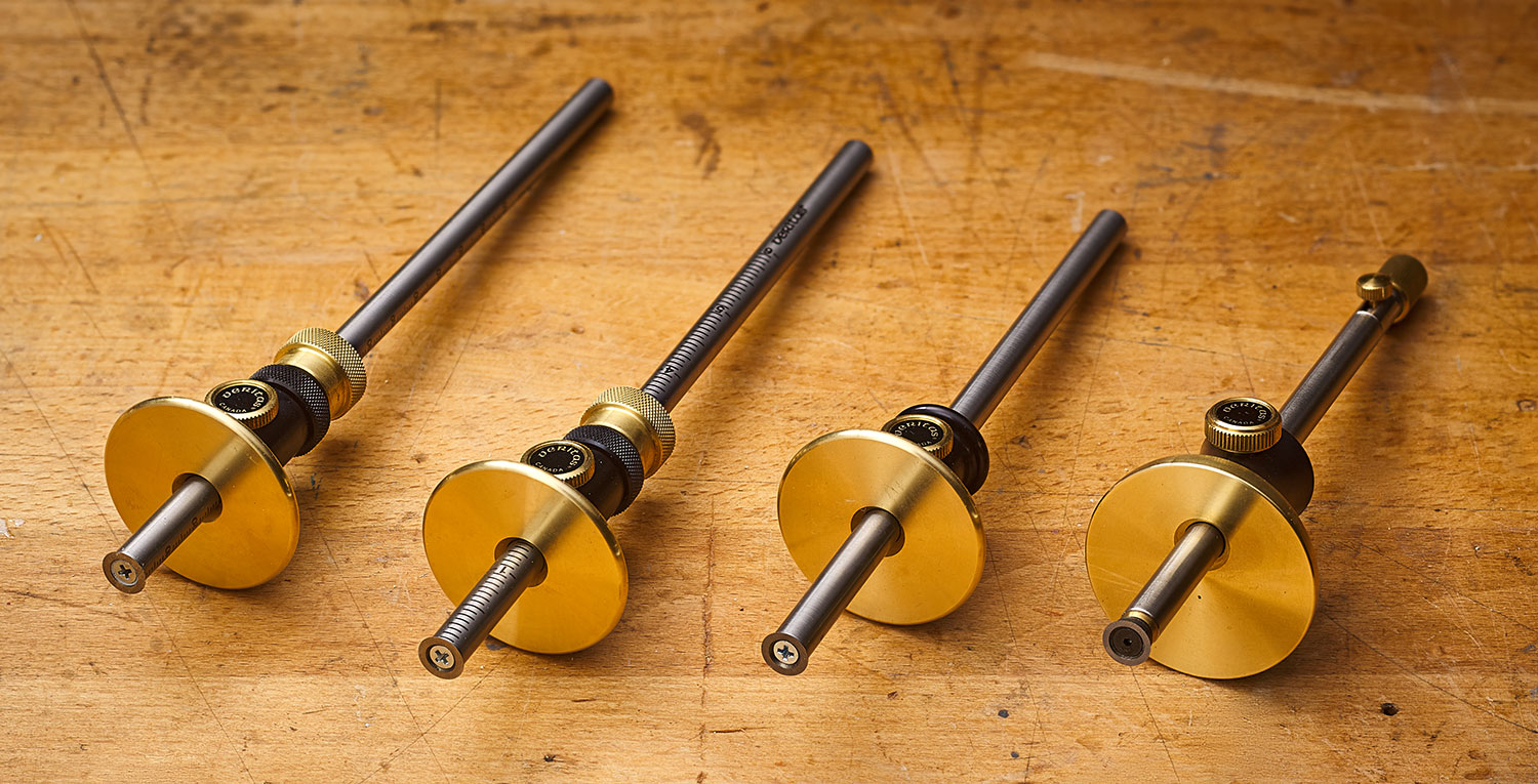 Four types of Veritas standard and micro-adjust wheel marking gauges arranged on a wooden workbench.