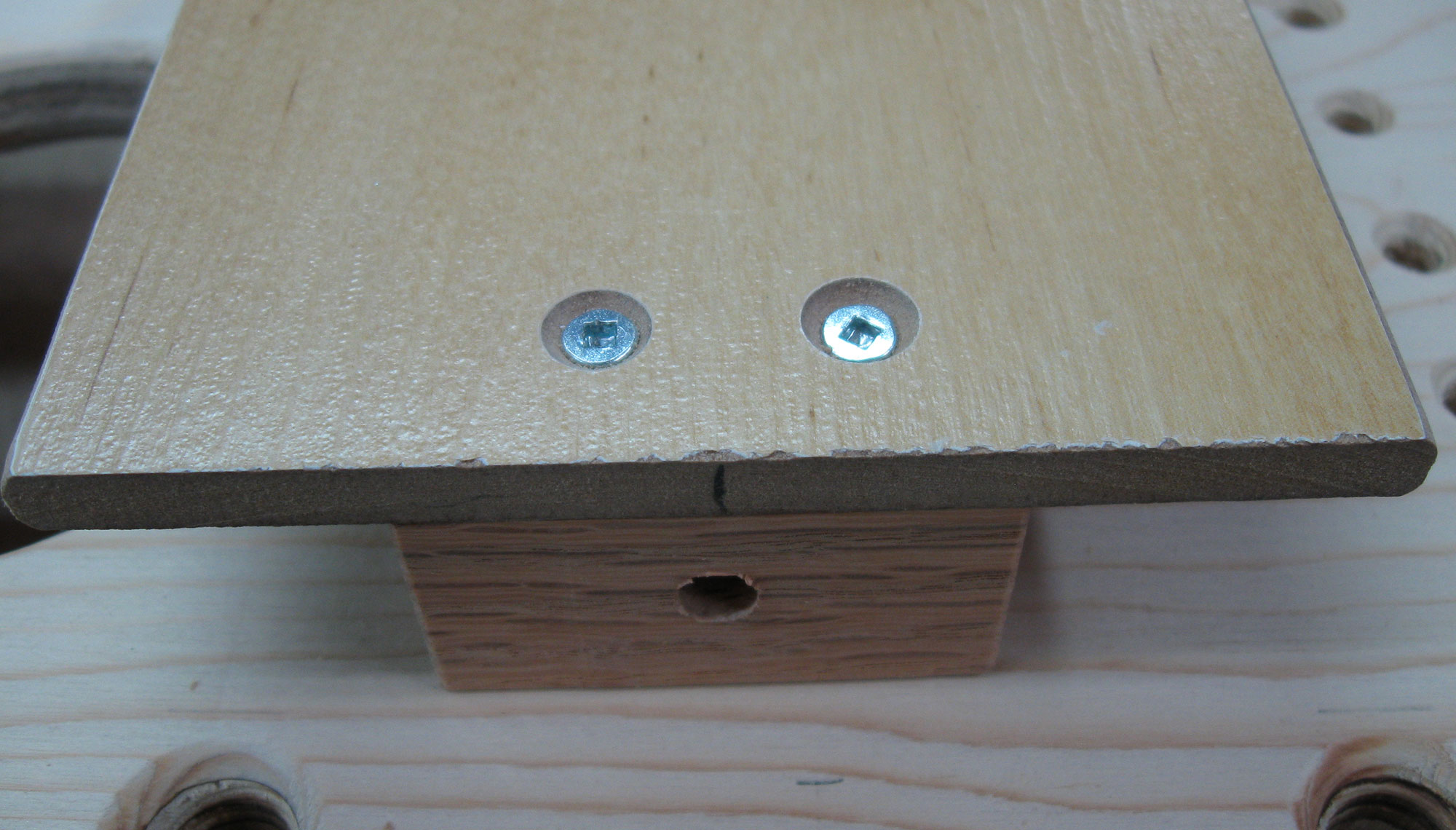 Hardwood block secured to jig using two flat-head wood screws.