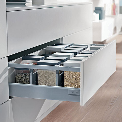 Drawer slides displayed on the side of an open kitchen cabinet drawer