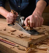 A woodworker uses a Veritas custom bench plane to smooth a wooden panel