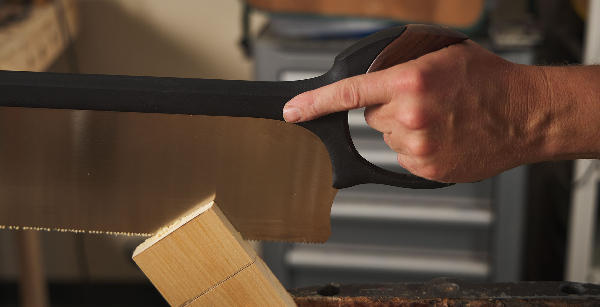 Holding the saw with a three-fingered grip while cutting