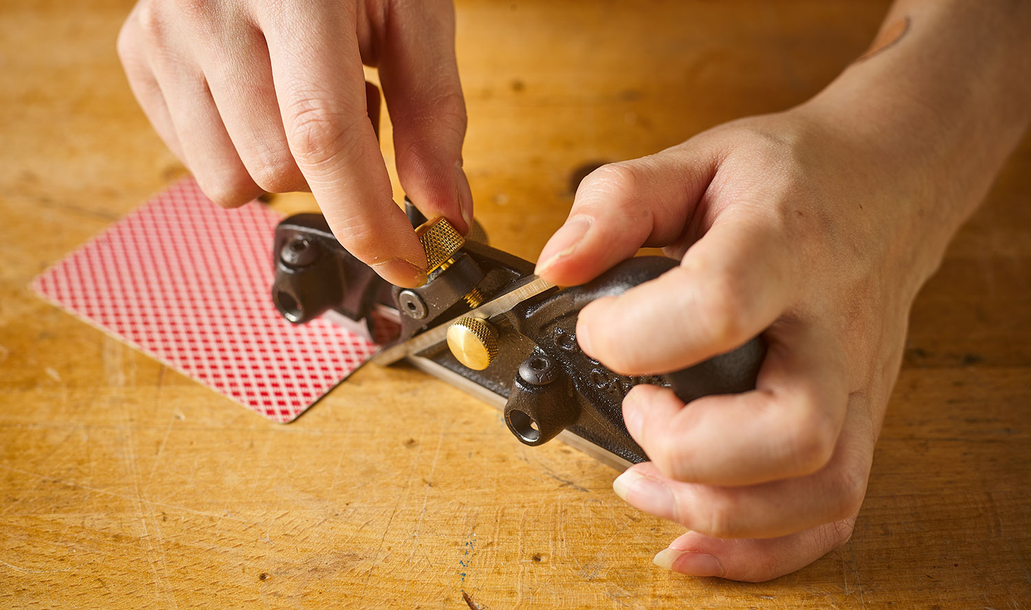 Setting blade projection on a box-maker’s plow plane, using a playing card as a shim under the skate.