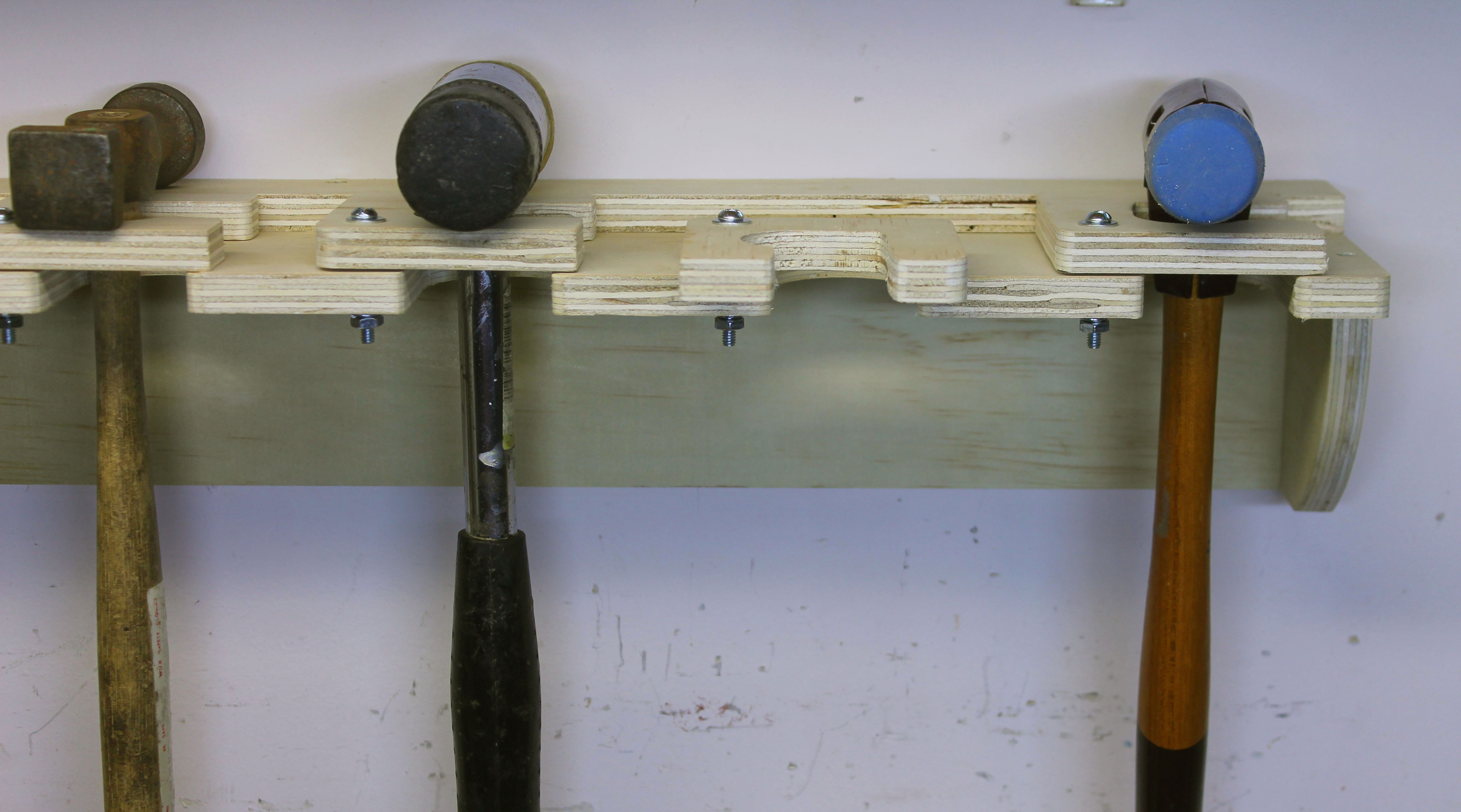 Porte-outils contenant un marteau et deux masses, avec un espace de rangement libre.